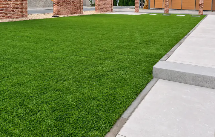 Neu angelegte Kunstrasenfläche mit präzisen Anschlüssen an Terrasse und Pflaster