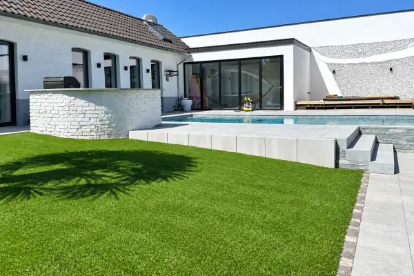 Schwimmfertiger Gartenpool mit heller Poolumrandung und gestalteter Rasenfläche